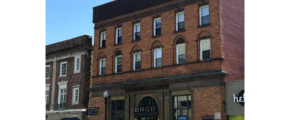 a row of cars parked in front of a tall brick building