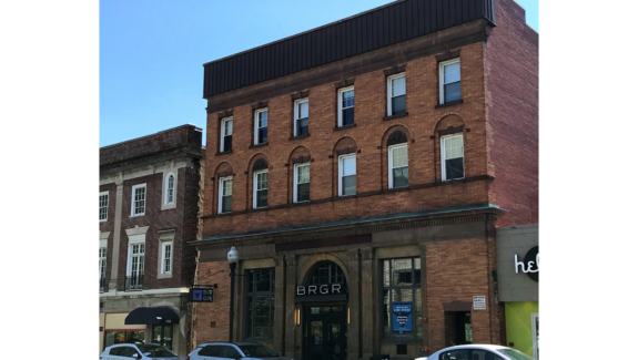 a row of cars parked in front of a tall brick building