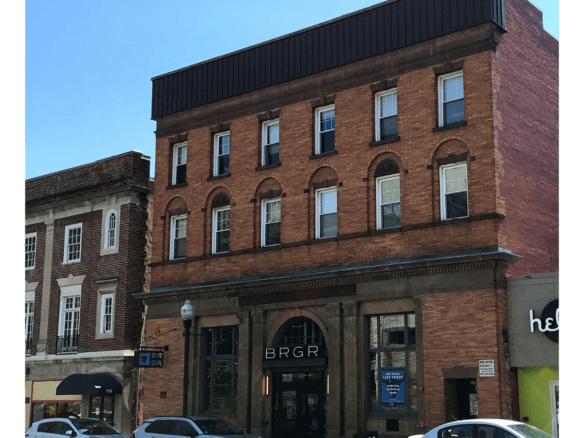 a row of cars parked in front of a tall brick building