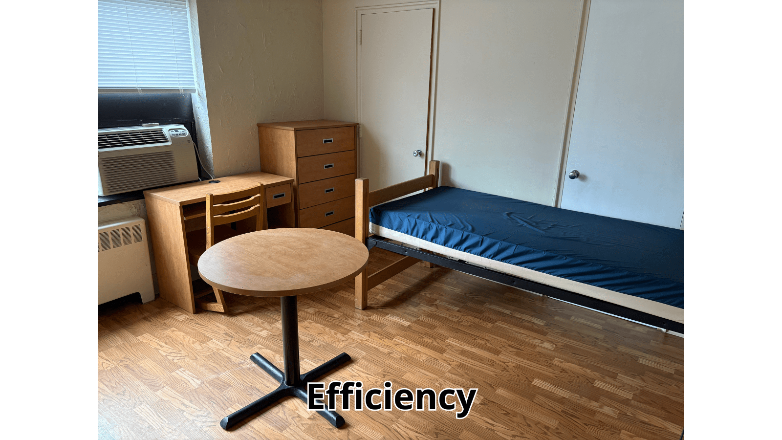Efficiency dorm room with bed, desk, and table