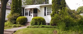 Exterior of a home with white siding, black shutters, and covered front entry.