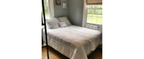 Bedroom with queen bed and window unit fan.