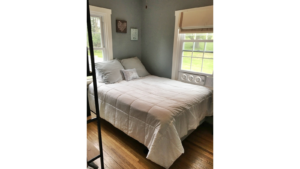 Bedroom with queen bed and window unit fan.