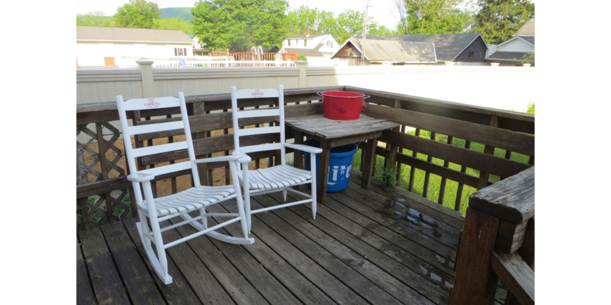 Wood deck with two white rocking chairs and wooden table.