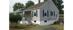 Exterior of building with gray siding and dark blue shutters.