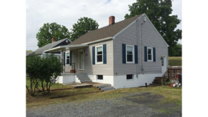 Exterior of building with gray siding and dark blue shutters.