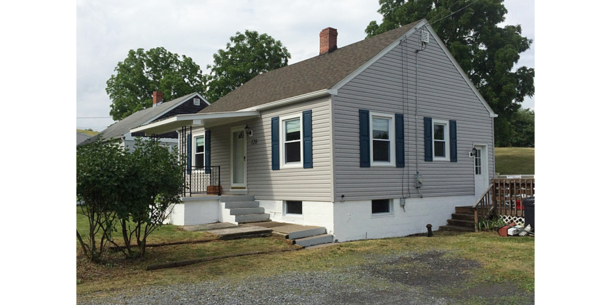 Exterior of building with gray siding and dark blue shutters.