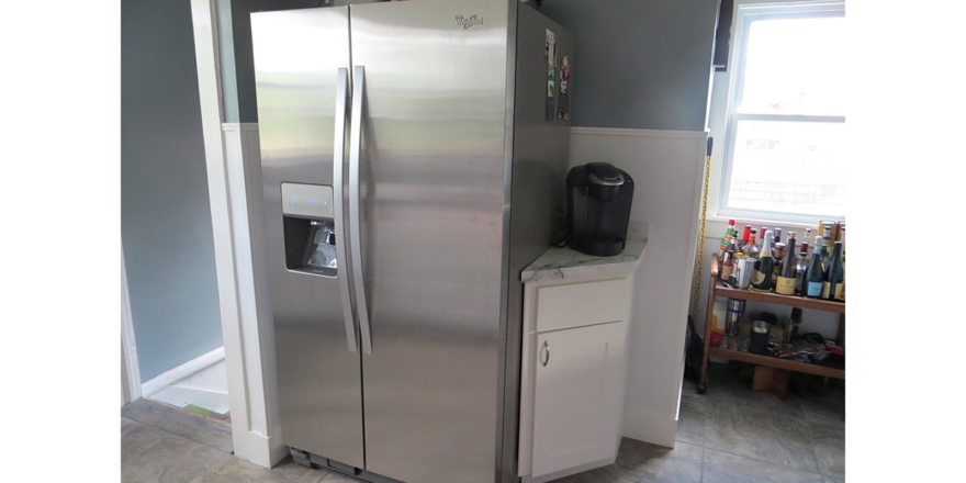 Kitchen with stainless steel fridge, small corner cabinet and bar cart