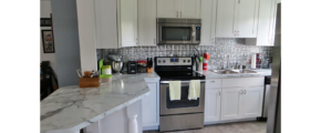 Kitchen with white cabinets, stainless steel appliances and white counter tops