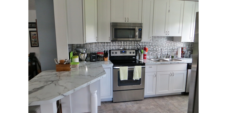 Kitchen with white cabinets, stainless steel appliances and white counter tops
