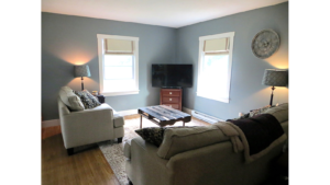 Living room with gray couch and love seat, industrial-style coffee table, two floor lamps and a TV