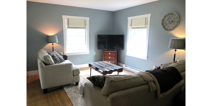 Living room with gray couch and love seat, industrial-style coffee table, two floor lamps and a TV