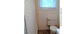 Bathroom with wood-style floor, toilet, shower with curtain, and window