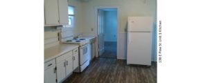 Kitchen with wood-style floor, white appliances, white cabinets, and light-colored countertops