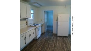 Kitchen with wood-style floor, white appliances, white cabinets, and light-colored countertops