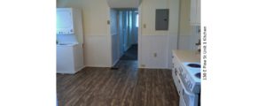 Kitchen with wood-style floor, stackable washer/dryer, white appliances, white cabinets, and light-colored countertops