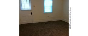 Unfurnished, carpeted living room with window and front door