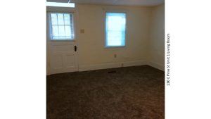 Unfurnished, carpeted living room with window and front door