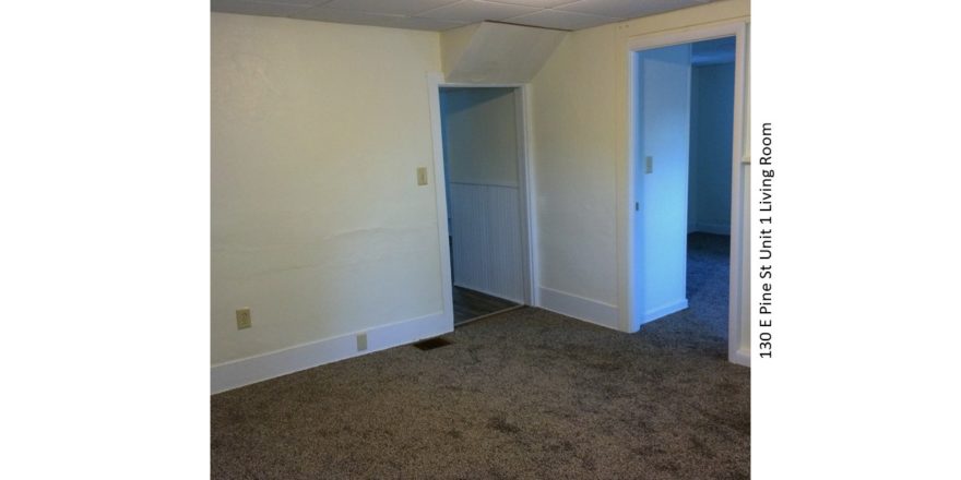 Unfurnished, carpeted living room with drop ceiling.