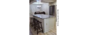 Kitchen with stainless steel fridge, dining table, and barstool seating at the island
