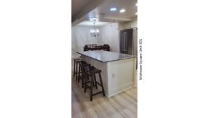 Kitchen with stainless steel fridge, dining table, and barstool seating at the island