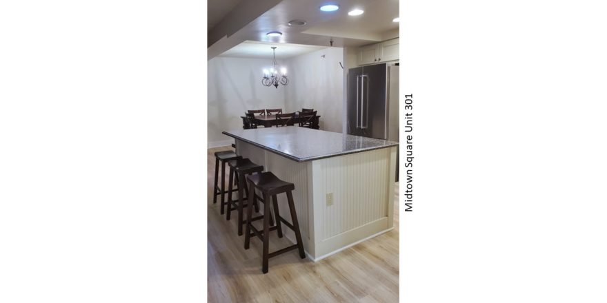 Kitchen with stainless steel fridge, dining table, and barstool seating at the island