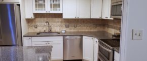 Kitchen with wood-style flooring, white cabinets, stainless steel appliances, and backsplash
