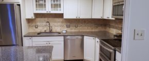 Kitchen with wood-style flooring, white cabinets, stainless steel appliances, and backsplash