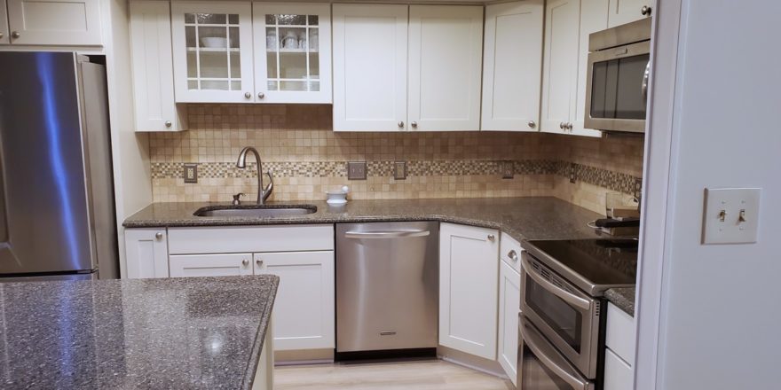 Kitchen with wood-style flooring, white cabinets, stainless steel appliances, and backsplash