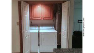 Laundry closet with washer/dryer and three cabinets above the machines