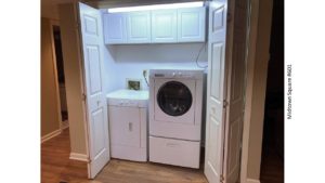 Laundry closet with washer/dryer and cabinets above the machines