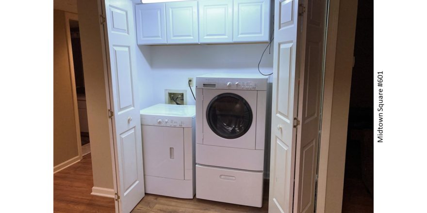 Laundry closet with washer/dryer and cabinets above the machines