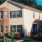Exterior of townhome with brick and siding as well as covered entrances and large windows
