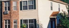 Exterior of townhome with brick and siding as well as covered entrances and large windows
