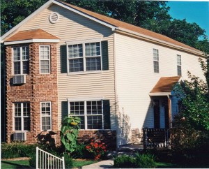 Exterior of townhome with brick and siding as well as covered entrances and large windows