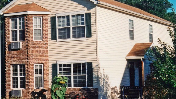 Exterior of townhome with brick and siding as well as covered entrances and large windows
