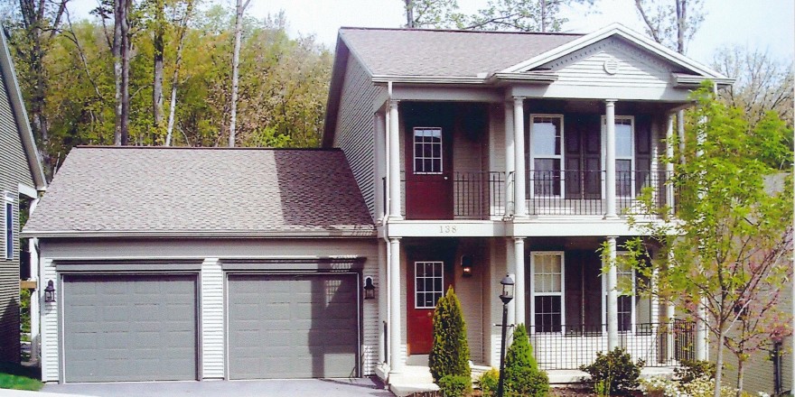 Exterior of two story house with large covered front porch, large balcony off the master bedroom, and large two car garage.