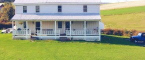 Exterior of duplex with large front yard, covered front porch, and siding with a metal roof