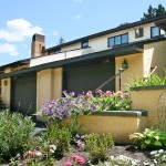 Exterior of duplex with large garage and yellow stucco siding