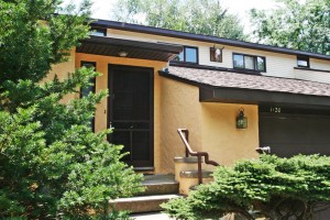 Exterior of duplex with large garage and yellow stucco siding