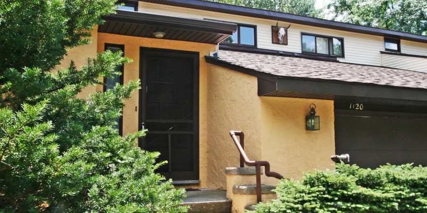 Exterior of duplex with large garage and yellow stucco siding