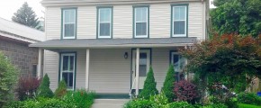 Exterior of house with tan siding and green trim