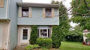 Exterior of townhouse with yellow brick and blue siding with yellow shutters