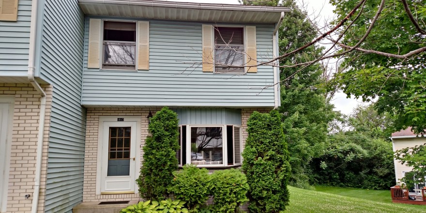 Exterior of townhouse with yellow brick and blue siding with yellow shutters