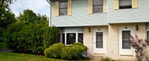 Exterior of townhouse with yellow brick and blue siding with yellow shutters