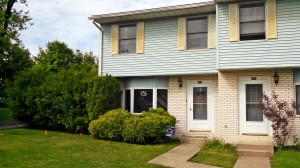 Exterior of townhouse with yellow brick and blue siding with yellow shutters