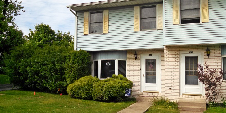 Exterior of townhouse with yellow brick and blue siding with yellow shutters