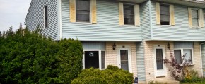 Exterior of townhouse with yellow brick and blue siding with yellow shutters