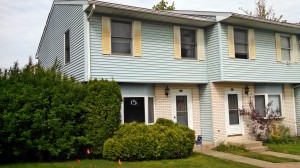 Exterior of townhouse with yellow brick and blue siding with yellow shutters