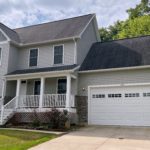 Exterior of two story house with covered front porch, garage, siding, stone, and landscaping.